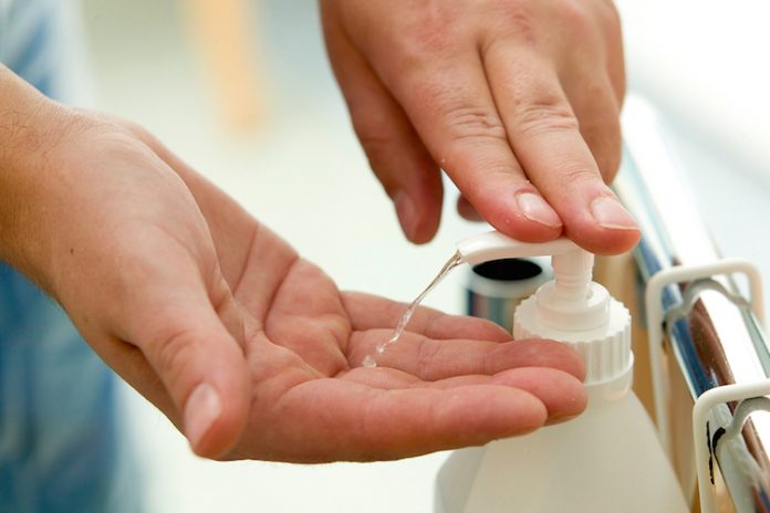Close up of hands squirting disinfectant from a pump bottle