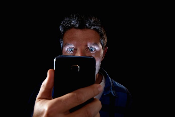 young man looking intensively mobile phone screen