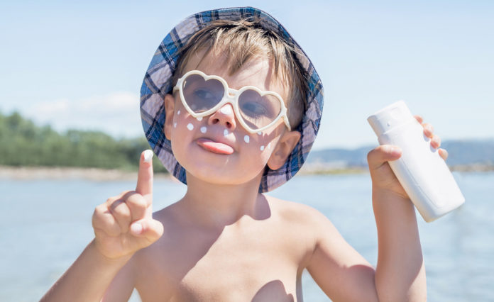 Sunscreen is on hipster boy face before tanning. Beach.