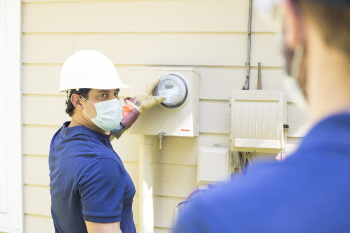 Electrical repair men working on outside meter of home. BOLLETTE