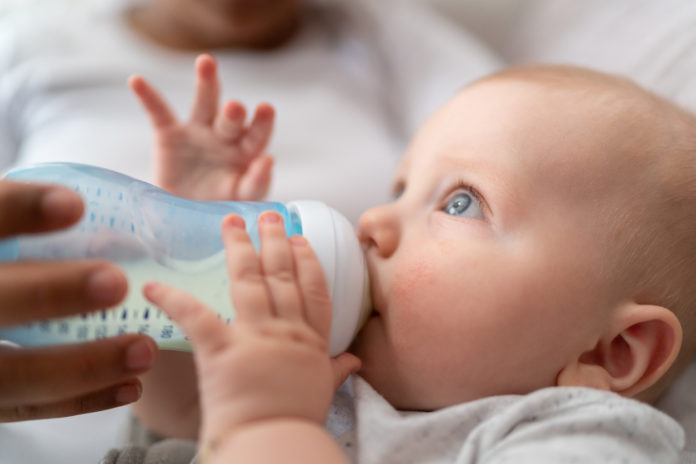 Baby boy drinking milk from milk bottle LATTE ARTIFICIALE