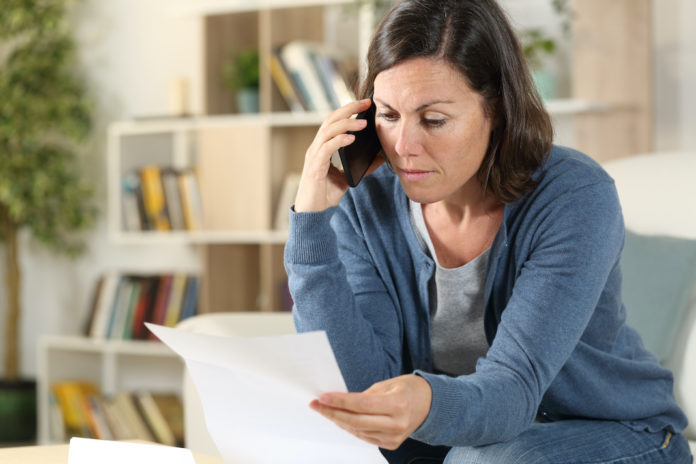 Adult woman calling on phone checking letter at home costi di migrazione