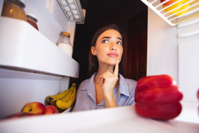 CALDO FRIGO Pensive housewife looking into fridge, view from inside CALDO FRIGO