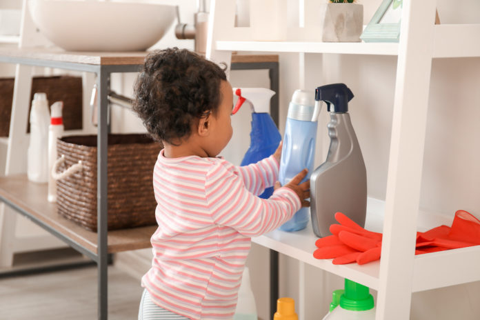 Little African-American baby playing with washing liquids at home. Child in danger bambini
