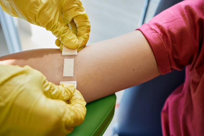 Nurse patches hand of child patient with band-aid after taking blood sample from vein for analysis in medical laboratory. Blood analysis bambini