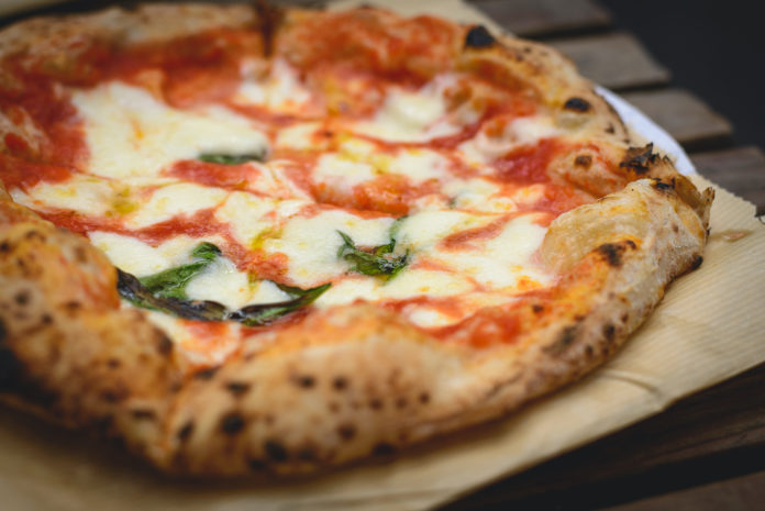 Close up view of a Margherita Neapolitan style pizza with buffalo mozzarella, tomato sauce and basil. Landscape format. pizza
