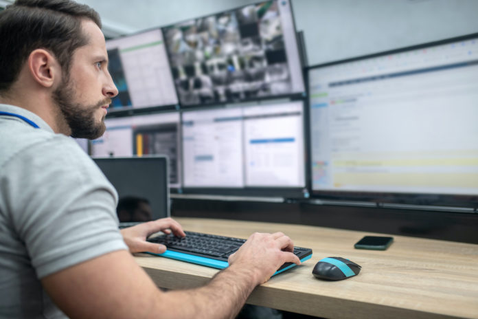 Attentive man with keyboard in front of computer screens ced interforze