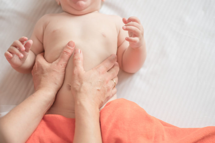 Massage stomach for little child infant makes a doctor massage therapist in a massage room with oil on bed. massage with colic tummy. manual therapy for childrens heals. motherhood. METEORISMO COLICHE BAMBINI