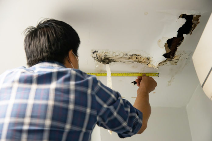 Worker repair and fixing ceiling panels damaged hole in the roof house from pipes water leakage. Office building or house problem from plumber system repairman service concept. DANNI