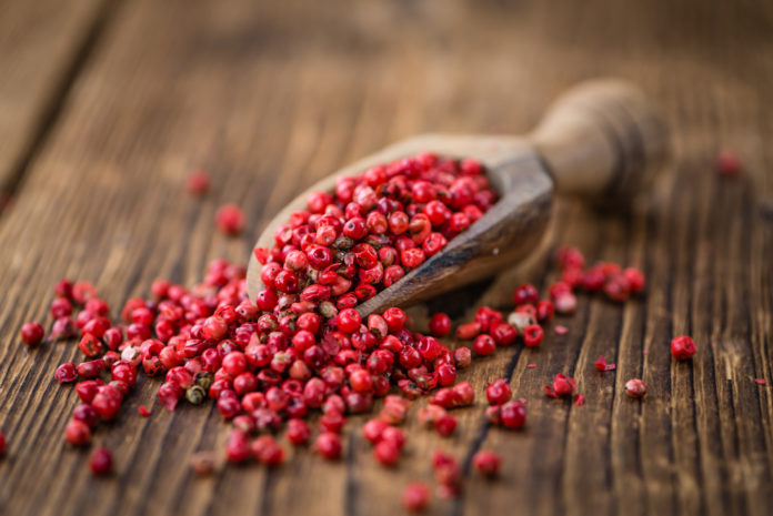 Portion of Pink Peppercorns on wooden background, selective focus pepe rosa