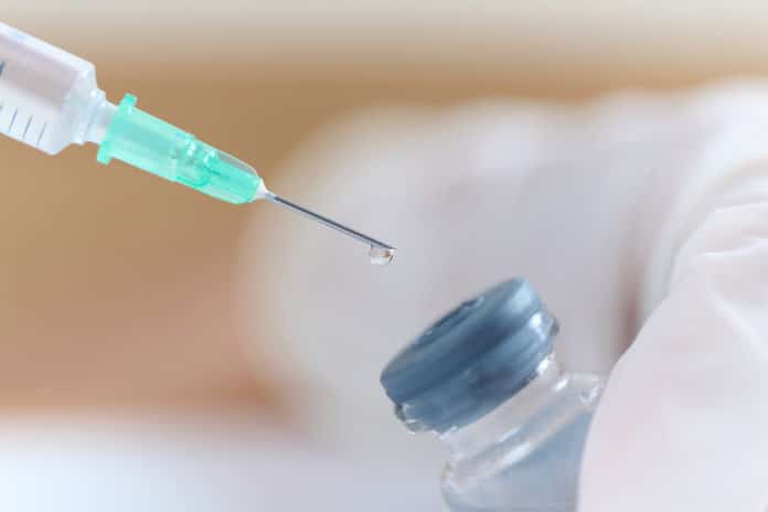 バイアル瓶から注射薬を吸う医師の手元 farmaci