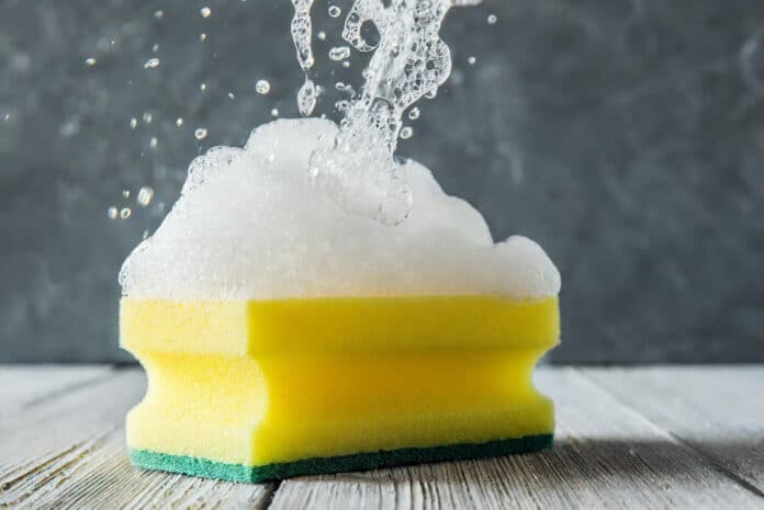 Yellow sponge with foam on grey background SPUGNETTE DA CUCINA