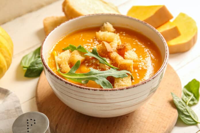 Bowl of delicious pumpkin cream soup with arugula and croutons on white background ZUPPE PRONTE