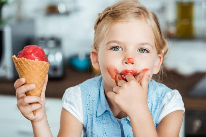 adorable little child licking finger while eating sweet ice cream and looking at camera GELATO BAMBINI
