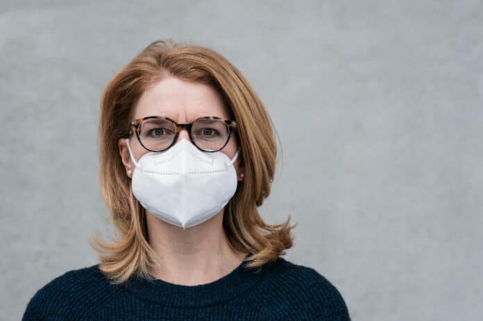 woman with white ffp2 mask and glasses, grey background with space for text and template MASCHERINE