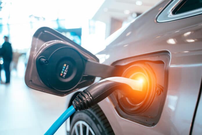 auto elettriche batterie Power supply plugged into an electric car being charged. Tesla Antitrust