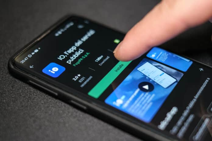 Man download new italian tax cash back app IO on a smartphone,credit card cashless