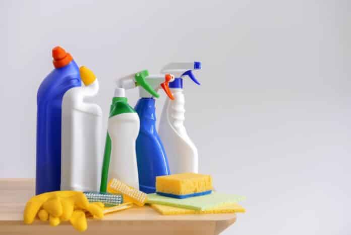 Cleaning supplies on wooden table against light background UFI