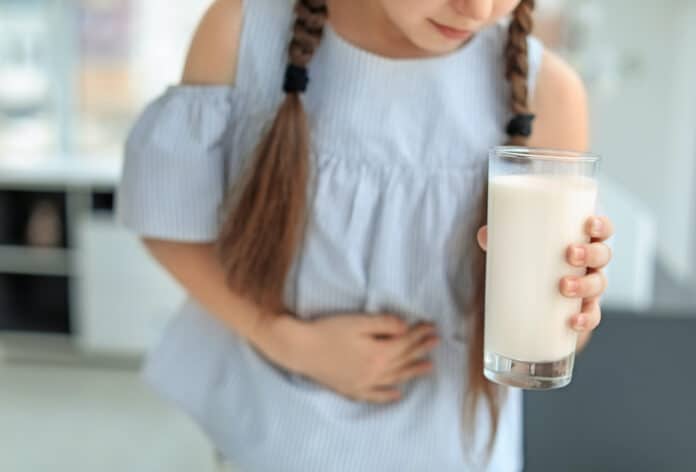 ALLERGIE ALIMENTARI TEST Little girl with dairy allergy holding glass of milk indoors ALLERGIE ALIMENTARI TEST