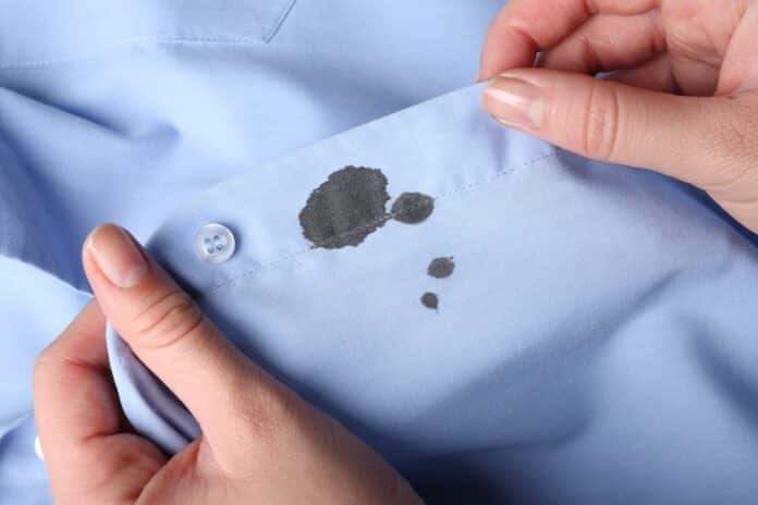 Woman holding shirt with black ink stain, closeup smacchiatore