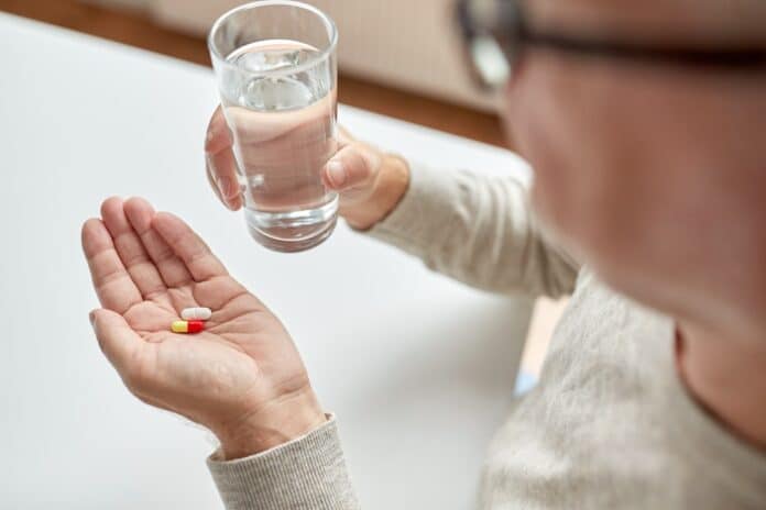 close up of old man hands with pills and water FARMACI ANZIANI