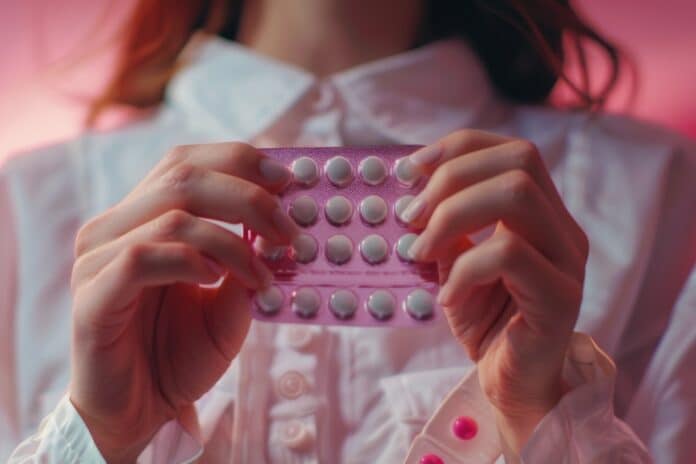 Woman is holding a pink pill in her hand DESOGESTREL CONTRACCEZIONE