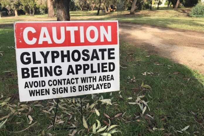 Cation Glyphosate being applied. Outdoor sign on city park path GLIFOSATO