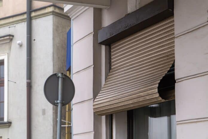 rolled up damaged external roller shutter on the window of the building. old damaged external roller shutter on the facade of the building from the street side. RIPARAZIONE DELLE TAPPARELLE