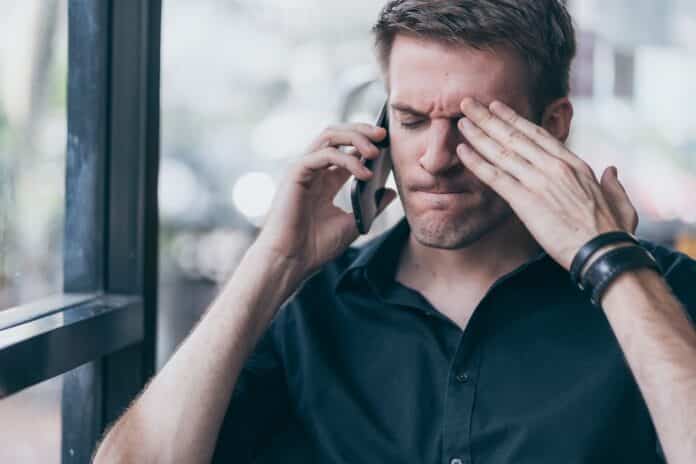 stressful white man caucasian angry and mad at smarthpone in cafe background telemarketing