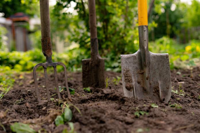 inserted shovel and pitchfork into the ground in the garden CONDOMINIO GIARDINO PRIVATO