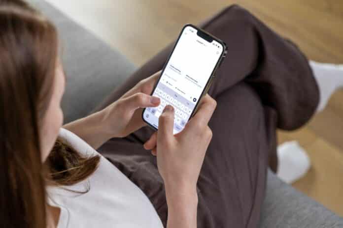 Poznan, Poland – April 14, 2025: Woman holding smartphone and typing message to ChatGPT AI assistant using mobile interface IA AI