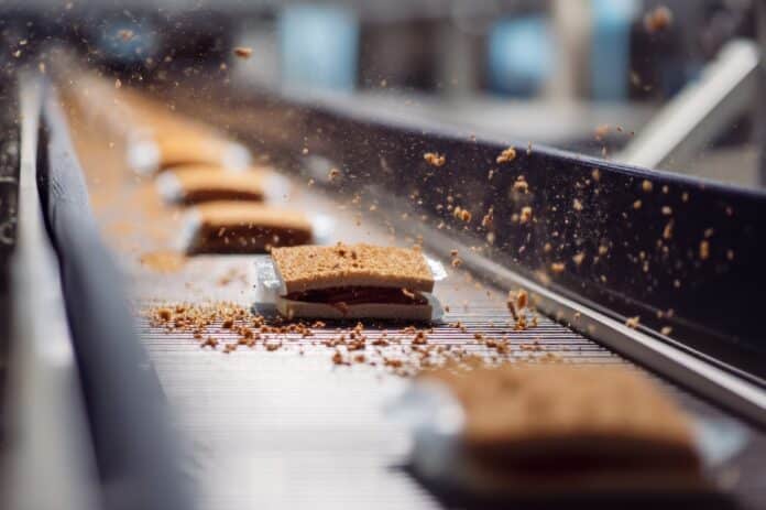 Ultraprocessed Food Conveyor belt with products in motion, showcasing a manufacturing process. ultraprocessati