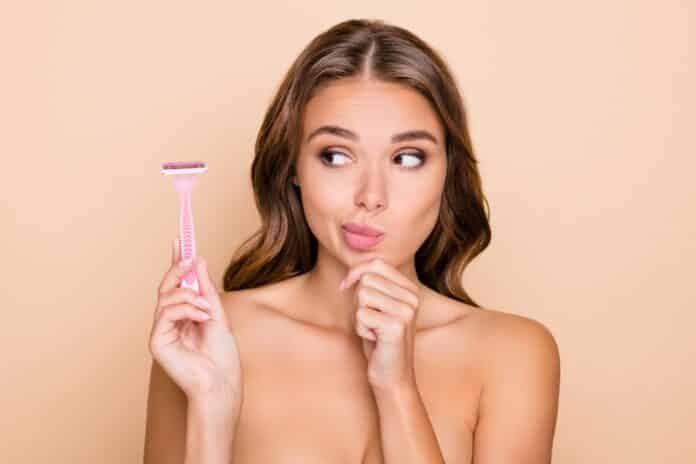 Photo of young thoughtful minded woman hold finger chin look at razor epilation depilation isolated on beige color background RASOI DA DONNA