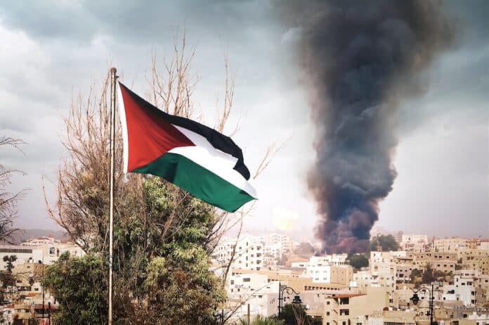 flag of Palestine on the mountain on the background of houses in the city.the war in the Middle East. explosion with black smoke in the city. GENOCIDIO
