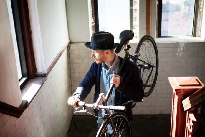 Man walking up stairs with bicycle CONDOMINIO