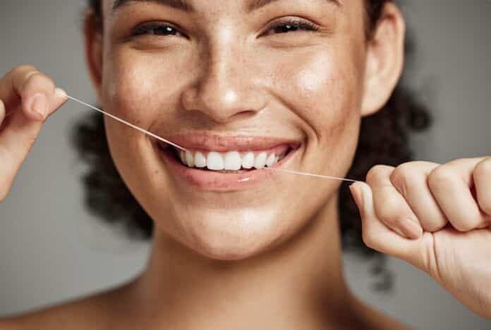 Woman portrait, dental floss and flossing teeth with smile for oral hygiene, health and wellness on studio background. Face of female happy about self care, healthcare and grooming for healthy mouth FILO INTERDENTALE