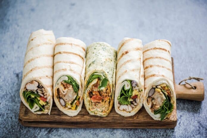 Mexican fajita wraps on serving board, copy space WRAP