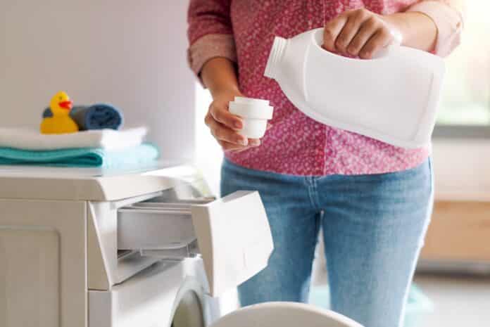 Woman pouring laundry detergent in the cap ISOTIAZOLINONI