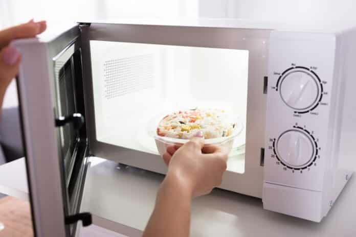 Woman Heating Food In Microwave Oven microplastiche