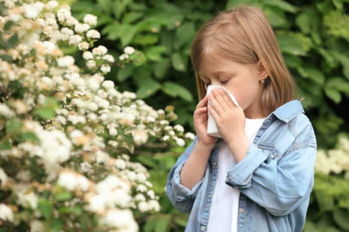 ALLERGIA POLLINI BAMBINILittle girl suffering from seasonal pollen allergy near blossoming tree on spring day ALLERGIA POLLINI BAMBINI