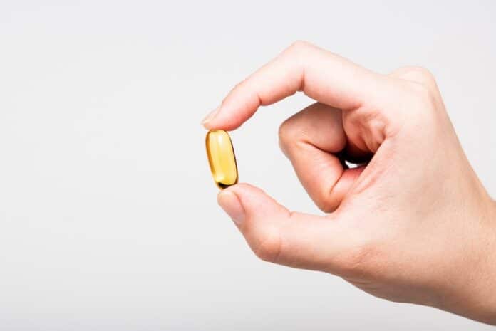Yellow Omega 3 capsule squeezed on white background OMEGA 3