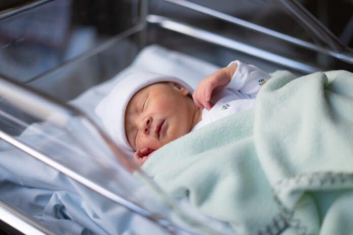 Close up portrait of adorable little newborn baby girl lying quiet at hospital crib hours after coming to life antibiotico