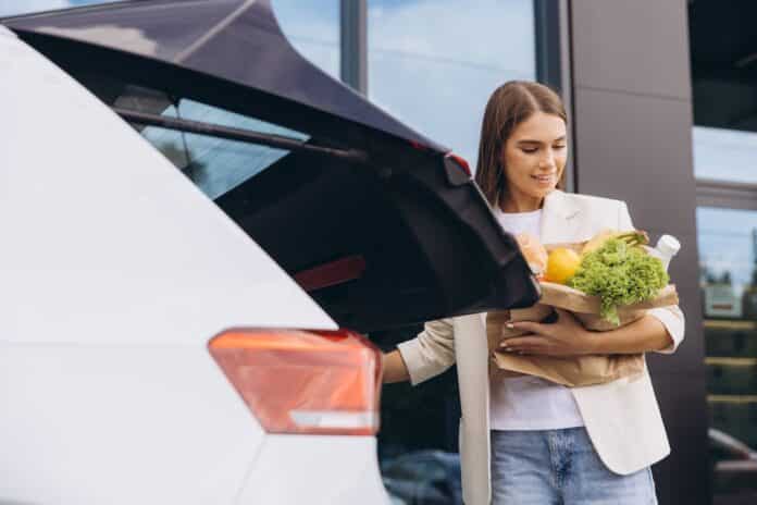 Woman Loading Groceries Into Car Trunk After Shopping SPESA AUTO CALDO