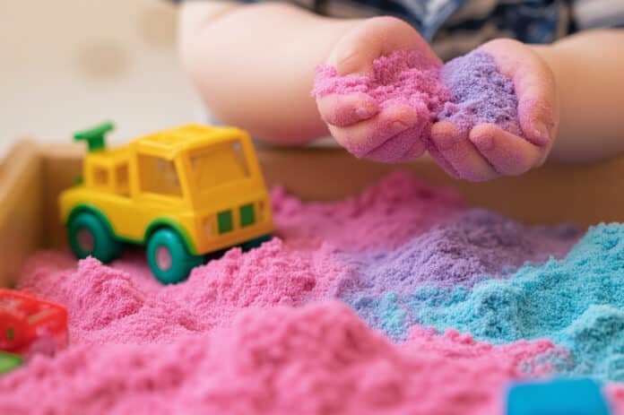 kid holding colorful sand. Fun sensory activity promoting coordination, touch exploration, and creativity.