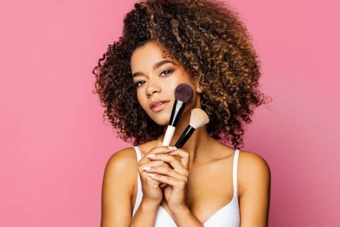 Portrait of the beautiful black woman with make-up brushes near attractive face COSMETICI TRUCCHI