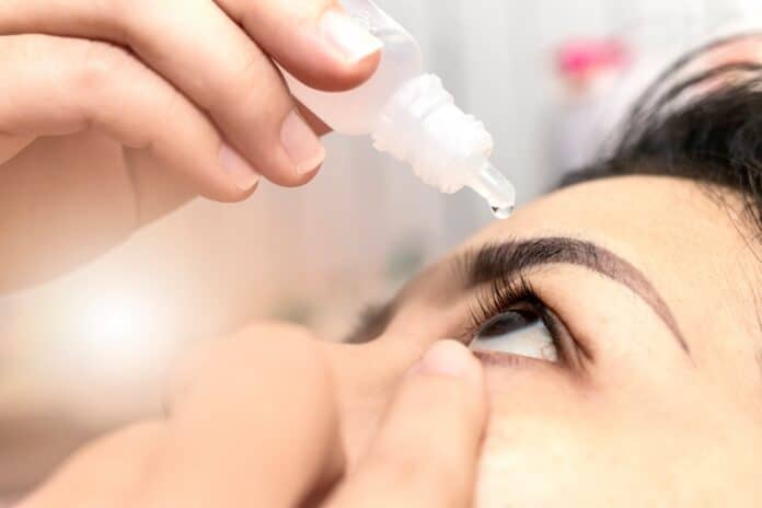 Closeup woman using eye drop. Woman applying eye drops healthcare concept. COLLIRIO
