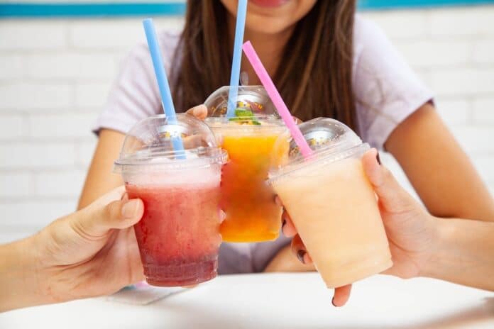 Friends holding drinking together fruity slush drinks.