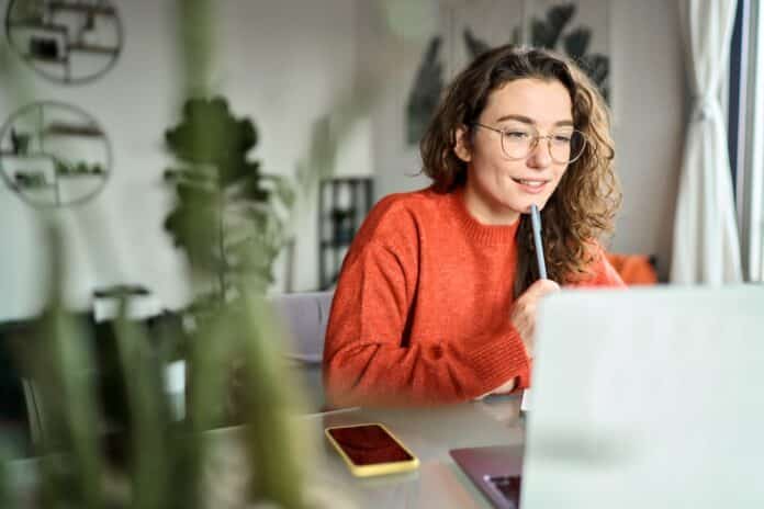 Young smiling woman student using laptop watching webinar writing at home. COLLOQUI LAVORO TRUFFA