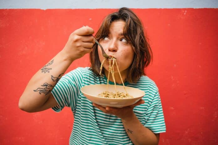 young woman eating pasta cute girl eating spaghetti having fun delicious food photography INDICE GLICEMICO PASTA