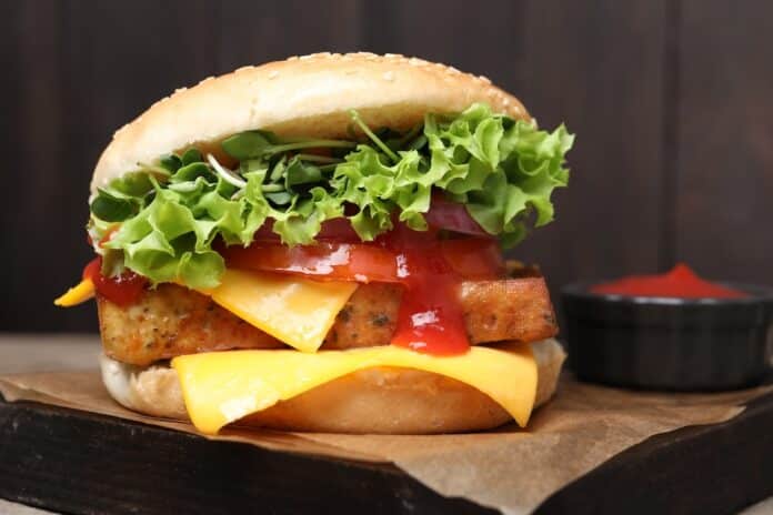 Delicious tofu burger served with sauce on board, closeup